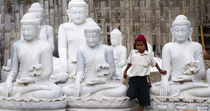 A Local Boy Passes Through A Group Of Buddha Statues Lining The Street In Mandalay.